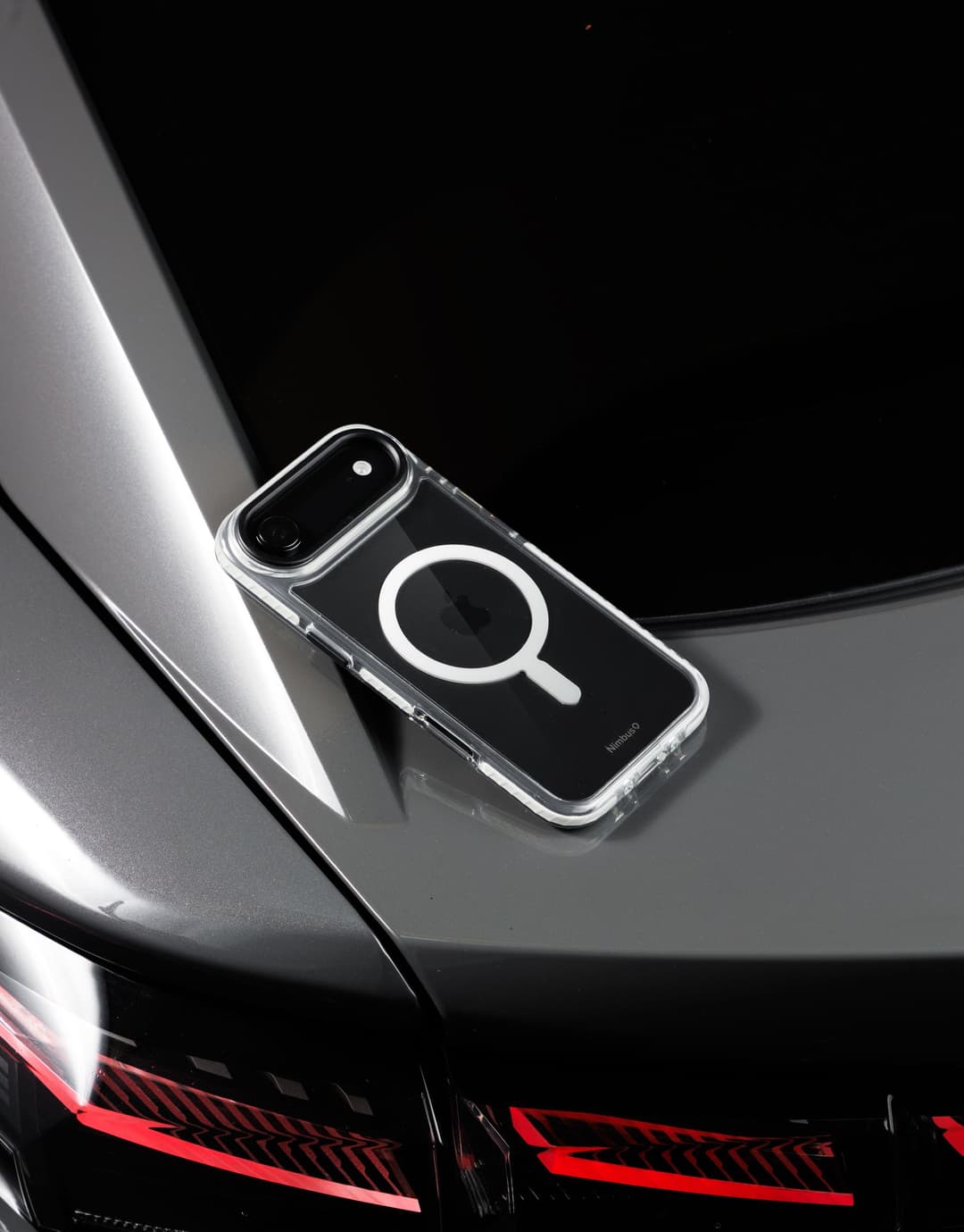 Nimbus9 Phantom 3 case with a visible MagSafe ring, resting on a car hood near the taillight at dusk
