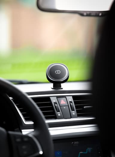 The empty black mount head on the dash above the air vents, the steering wheel blurred in the foreground and the car's own map screen below