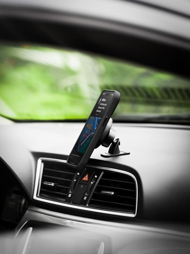 Side view of a phone held on the black dash mount, the ball joint and the head's edge in profile, the car's air vents below
