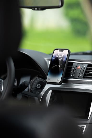 A phone held at the air vent, the vent clip hidden behind it, the hazard switch and vent louvres alongside