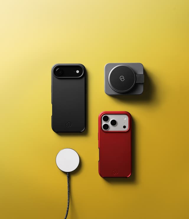 A black case, a red case, a gray magnetic car mount head and a white MagSafe charging puck laid out on a yellow ground