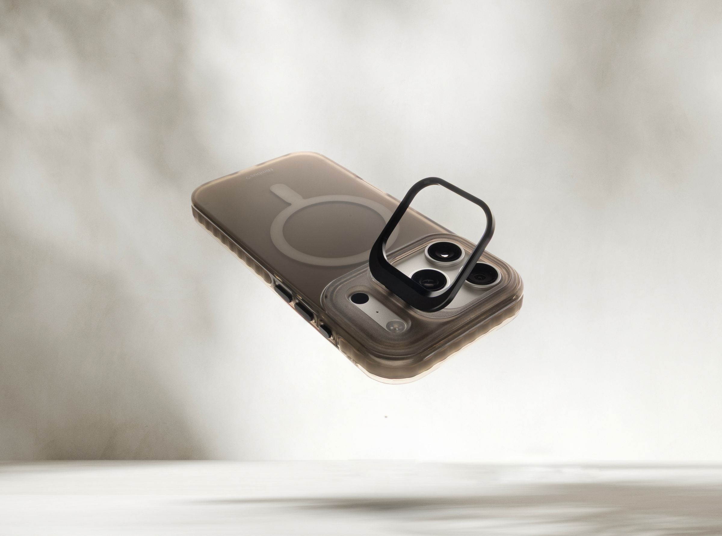 Stratus 2 case in Smoke floating over a pale haze, its integrated kickstand ring flipped open around the camera module, MagSafe ring visible