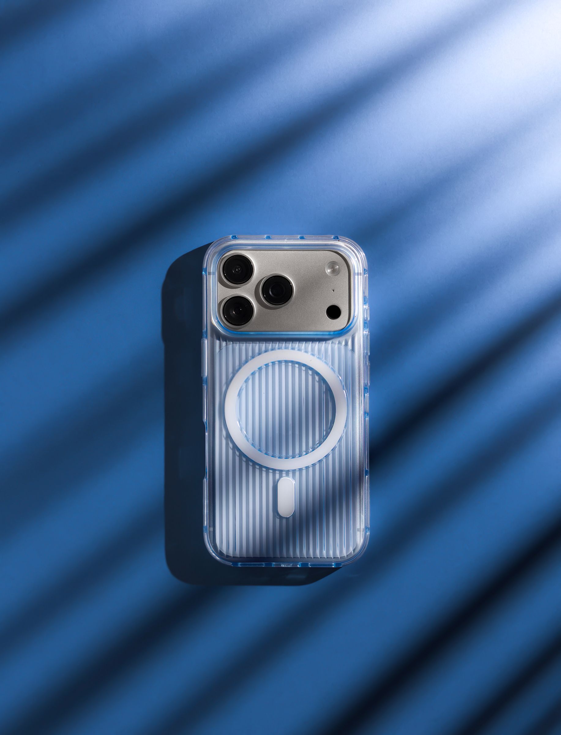Nimbus9 Alto 2 Clear case in Clear Blue on an iPhone, ribbed sides and MagSafe ring visible, set against a deep blue backdrop